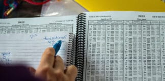 How To Read A Tide Table a person makes handwritten notes while scanning through a spiral bound tide table