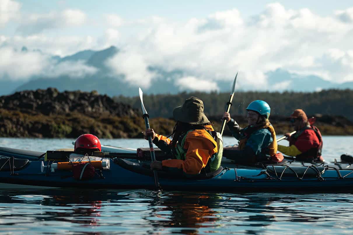 a group of sea kayakers paddling on the water