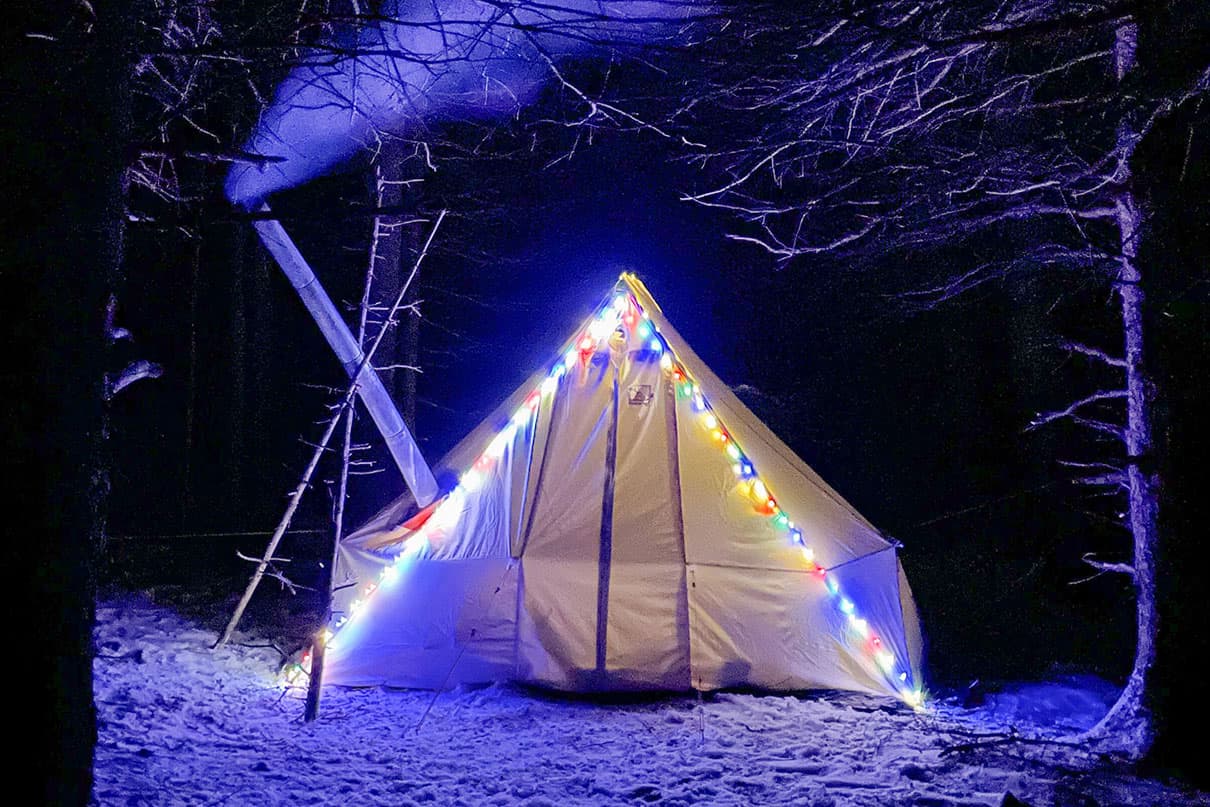 a hot tent with fairy lights along the triangular supports