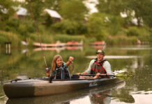 Get Started Kayak Fishing man sits in fishing kayak while young girl excitedly catches fish