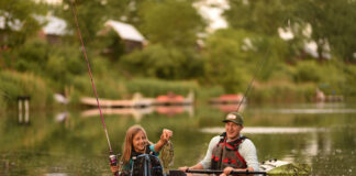 Get Started Kayak Fishing man sits in fishing kayak while young girl excitedly catches fish