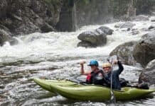 Whitewater Kayaking Hits the Big Screen in Apex Two women in green whitewater kayaks with rapids behind them
