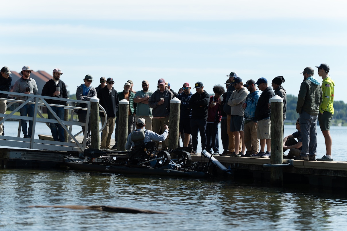 Anglers on dock watching someone on fishing kayak