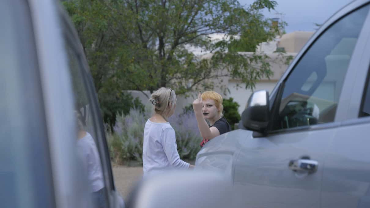 Young girl giving middle finger as she stands beside her grandmother