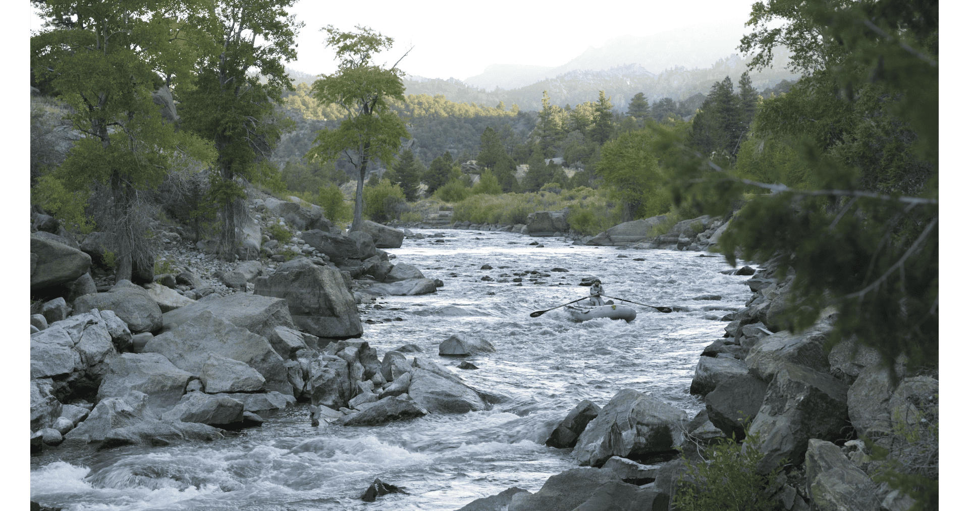 Woman in raft in middle of rapids on river