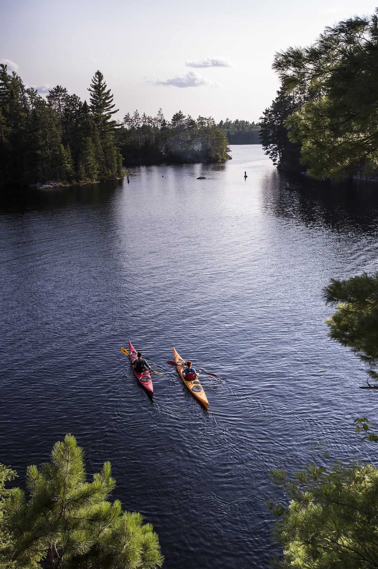 Two people in kayaks on narrow waterway