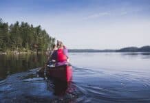 Guide to Canoe Tripping in Québec’s Kipawa Region Two people paddling in red canoe across lake