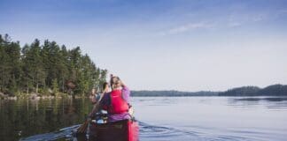 Guide to Canoe Tripping in Québec’s Kipawa Region Two people paddling in red canoe across lake