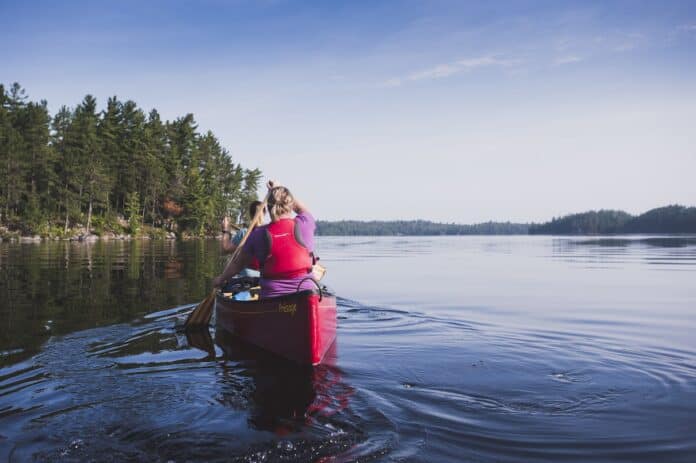 Kipawa Canoe Camping Two people paddling in red canoe across lake