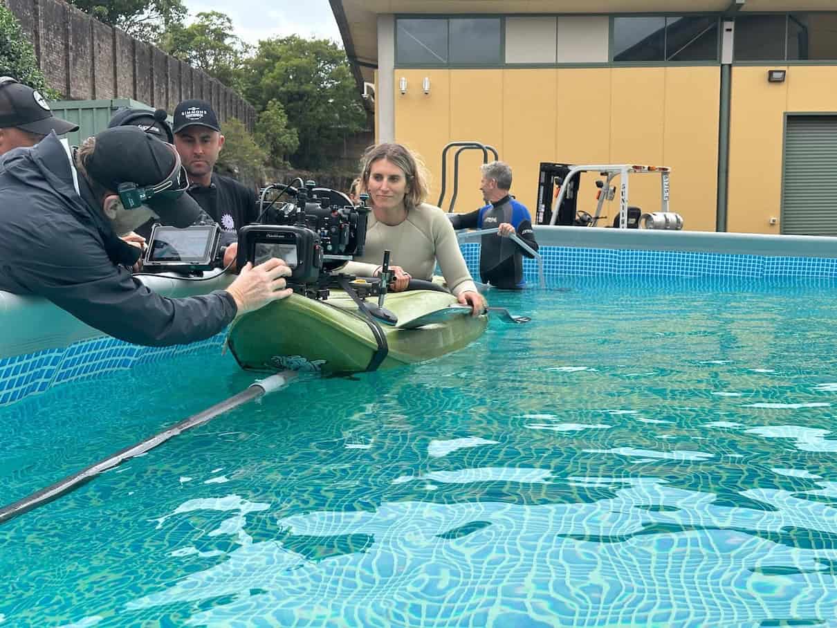Woman sitting in kayak in pool with camera on bow