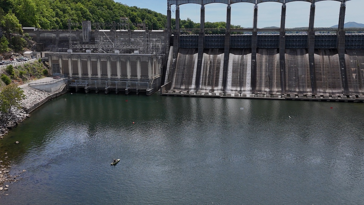Kayak angler fishing next to massive dam.