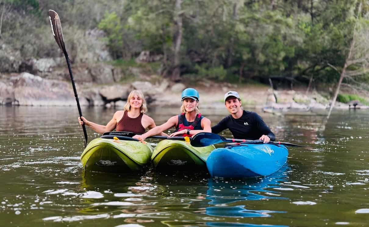 Two women and one man in whitewater kayaks on river