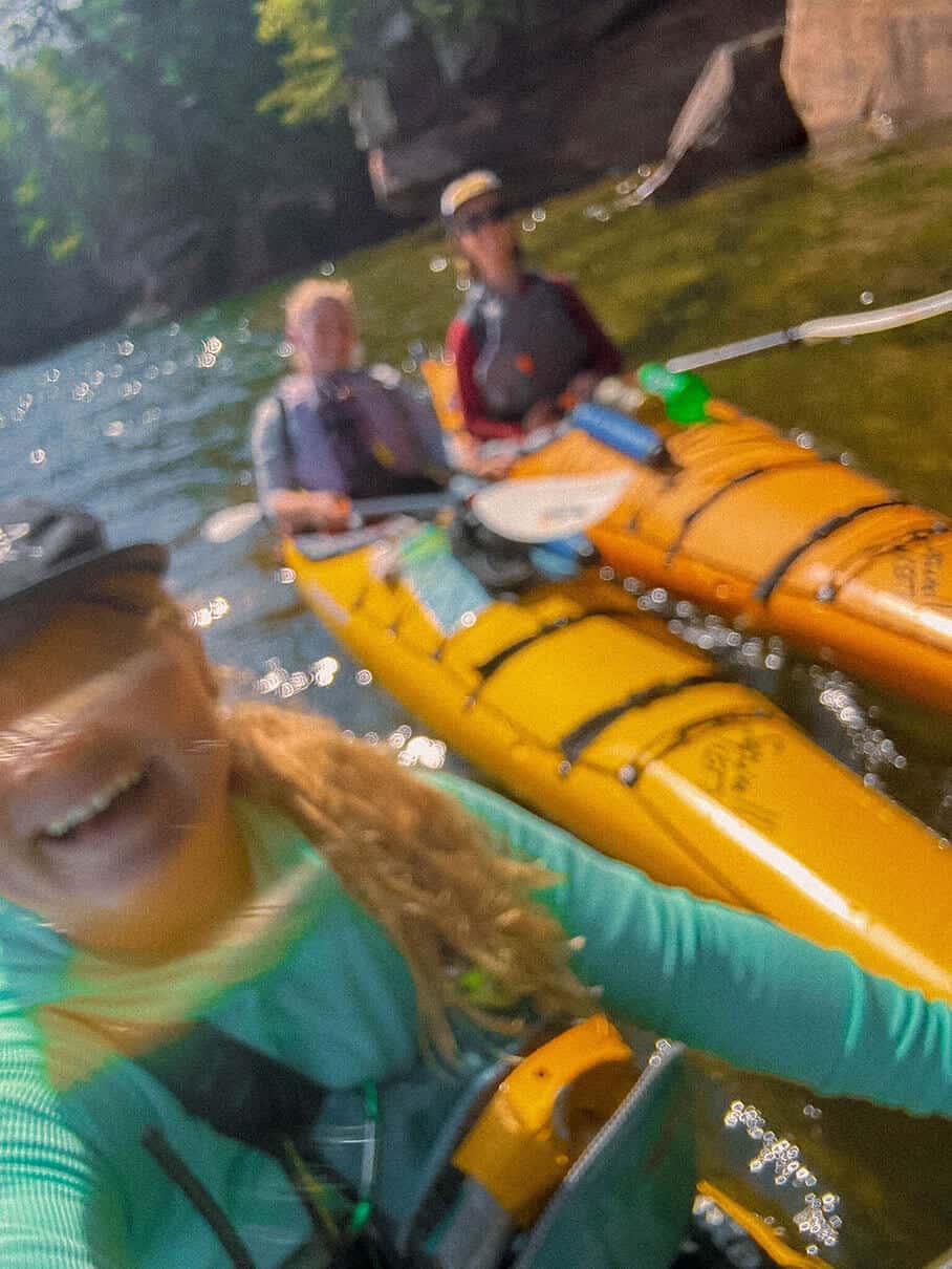 Maddy Marquardt smiles into the camera with friends on the background during a paddling trip