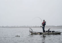 Lobster Rolling Through Maine man stands and fishes from a kayak during rainy weather in Maine