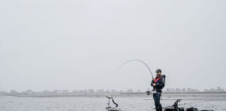 Lobster Rolling Through Maine man stands and fishes from a kayak during rainy weather in Maine