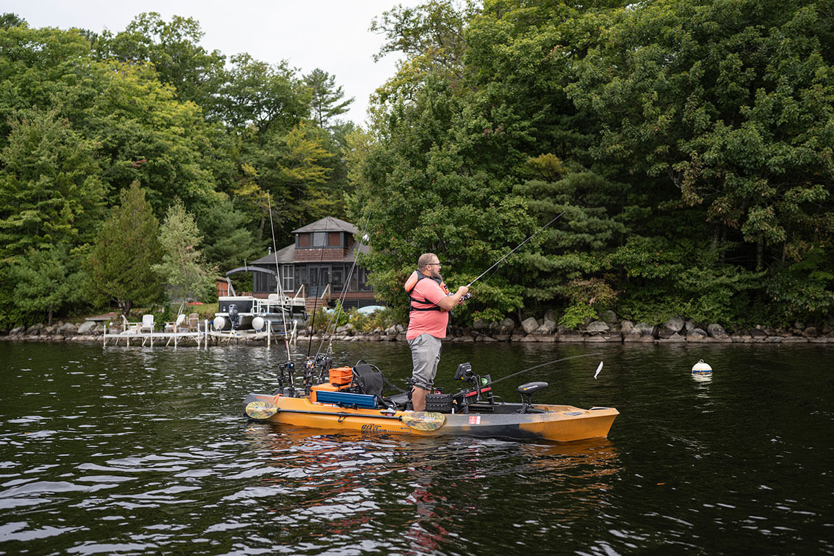 man stands and casts for bass from his kayak