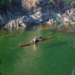 What’s In Editor Maddy Marquardt’s Sea Kayak Day Trip Guiding Kit Paddling Magazine Editor Maddy Marquardt in her sea kayak on a trip with vivid green water, rocks and surrounding foliage in the foreground