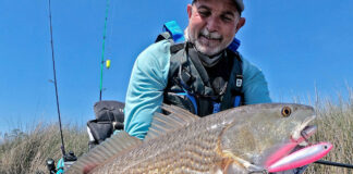 Learn To Catch Redfish On Topwater Lures kayak angler holds up a redfish caught with topwater lure