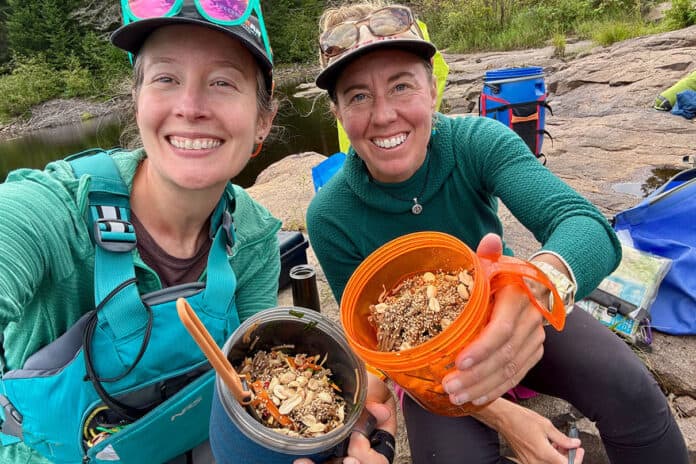Paddling Magazine editor-in-chief Kaydi Pyette and columnist Virginia Marshall pose at a canoe campsite with their trail salads