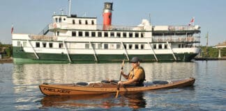 Kayak Review: Melker Värmdö man paddling Melker’s Värmdö kayak with a riverboat in the background