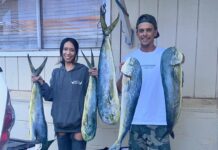 Man and woman standing in front of house holding fish