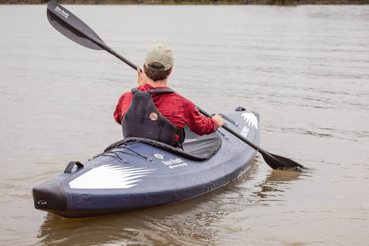 Paddler on lake in inflatable kayak.