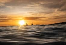 Why Survival Stories Make Us Better Paddlers two people paddle on swells at dusk