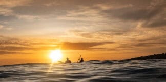 Why Survival Stories Make Us Better Paddlers two people paddle on swells at dusk