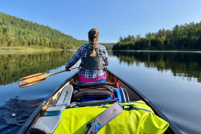 photo of woman paddling a laden canoe from the stern
