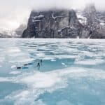 A Baffin Vacation, Love On Ice: Inside The Best Adventure Film Of 2026 Two people on ice pulling kayaks with mountain in background