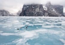 A Baffin Vacation, Love On Ice: Inside The Best Adventure Film Of 2026 Two people on ice pulling kayaks with mountain in background