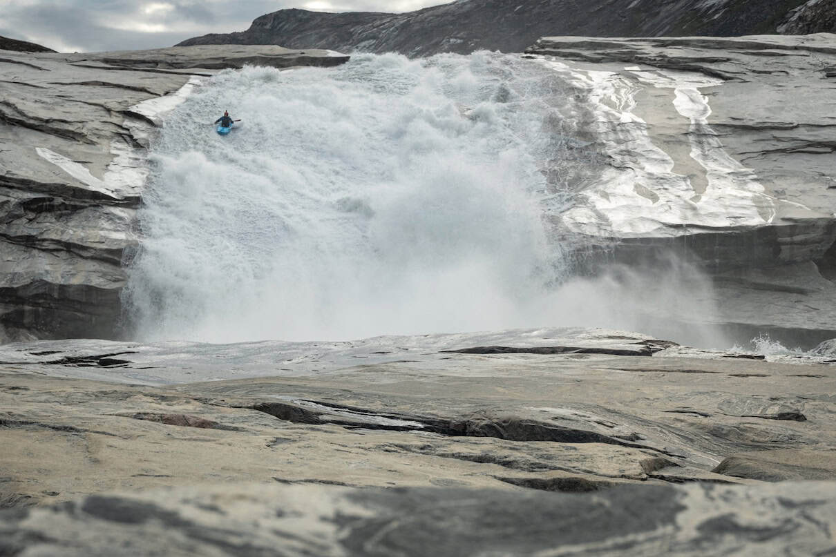 Person in blue whitewater kayak going down waterfall