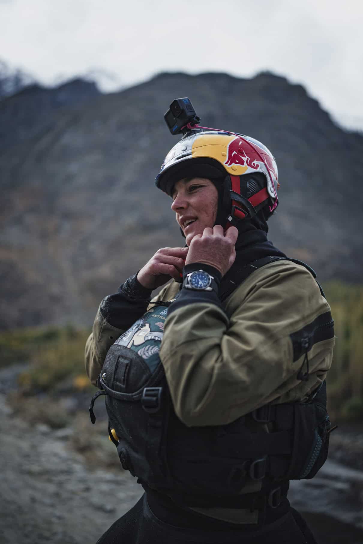 Woman putting whitewater kayak helmet on