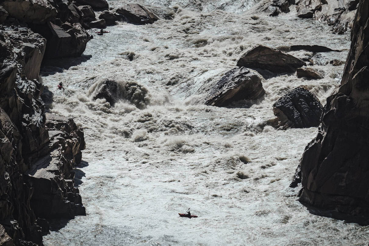 Small red boat in the middle of raging river