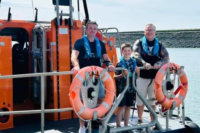 boy stands on boat with father and grandfather