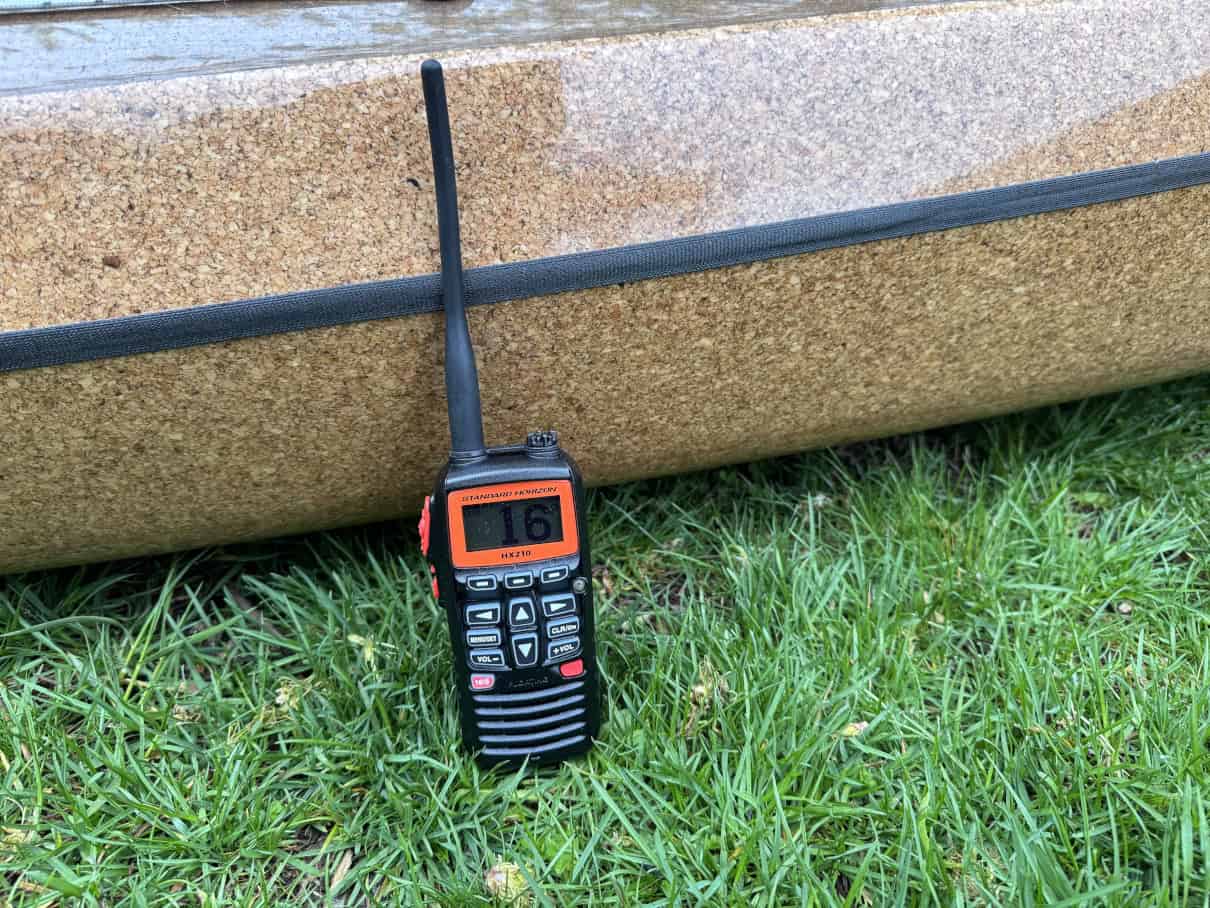 Standard Horizon handheld radio sitting on grass next to kayak.