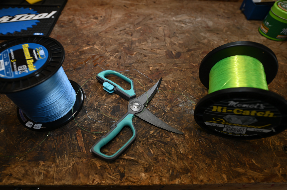 A pair of utility scissors next to fishing line.