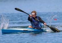 Man in sprint kayak on lake.