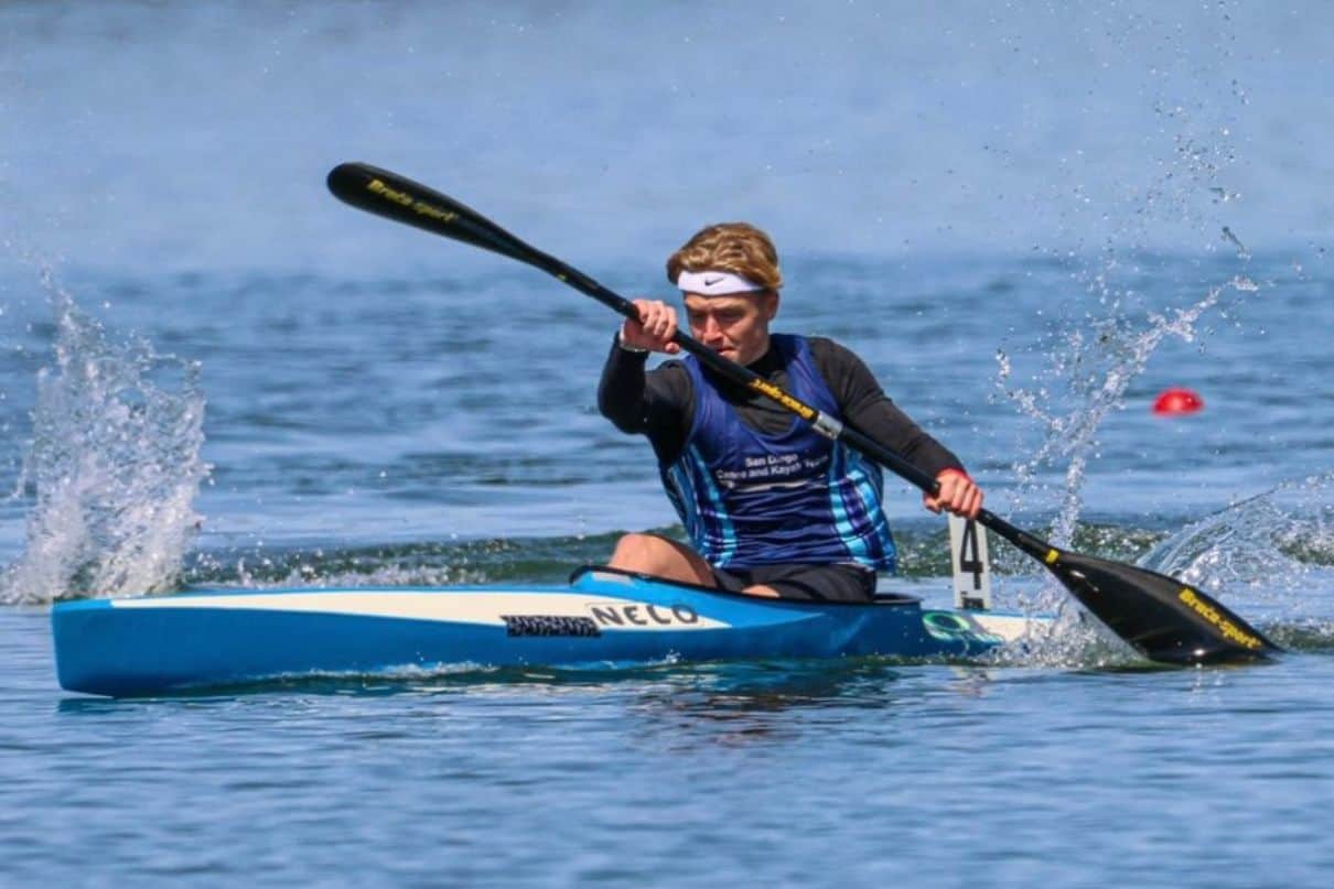 Man in sprint kayak on lake.