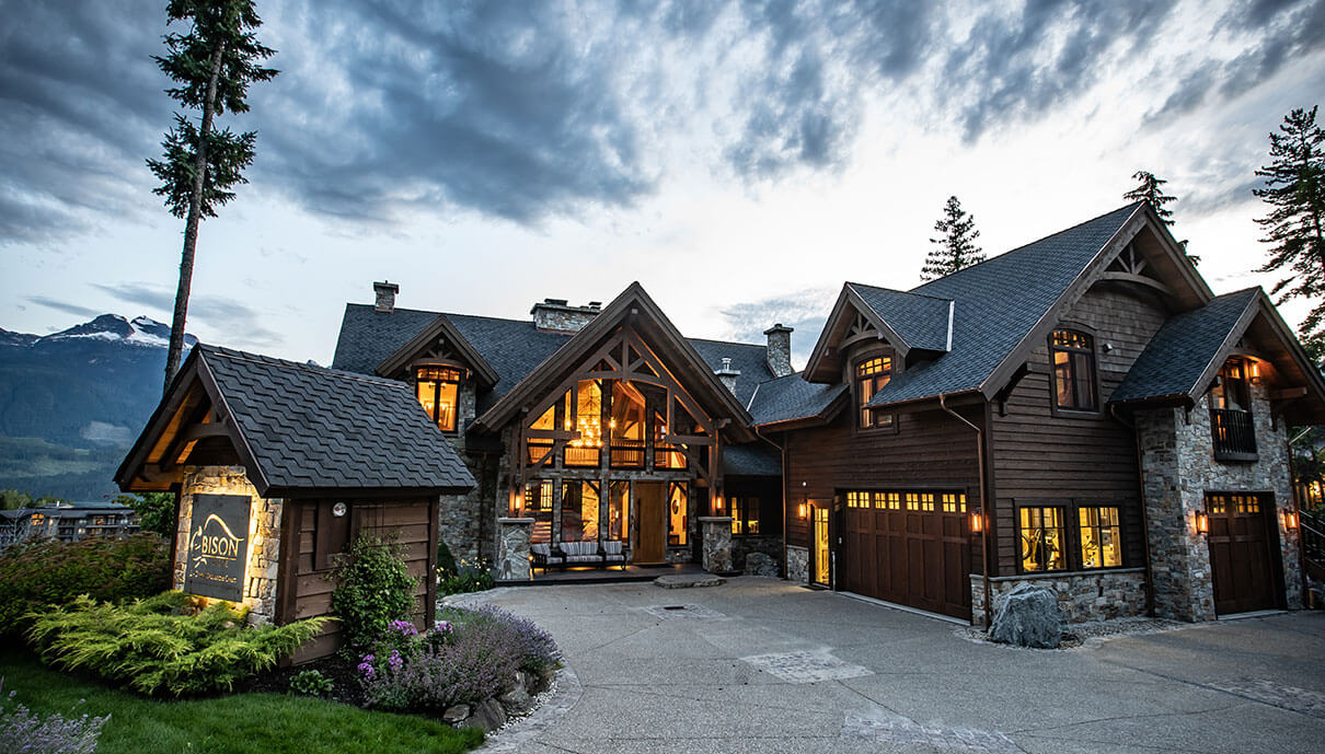 exterior of Bison Lodge in Revelstoke BC, a large stone and timber lodge with mountains behind