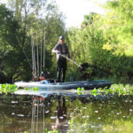 Pitch Bait Tactics That Work Man stands on his fishing kayak while demonstrating pitch bait tactics