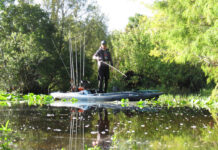 Pitch Bait Tactics That Work Man stands on his fishing kayak while demonstrating pitch bait tactics
