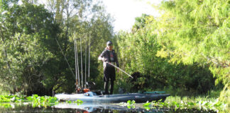 Pitch Bait Tactics That Work Man stands on his fishing kayak while demonstrating pitch bait tactics
