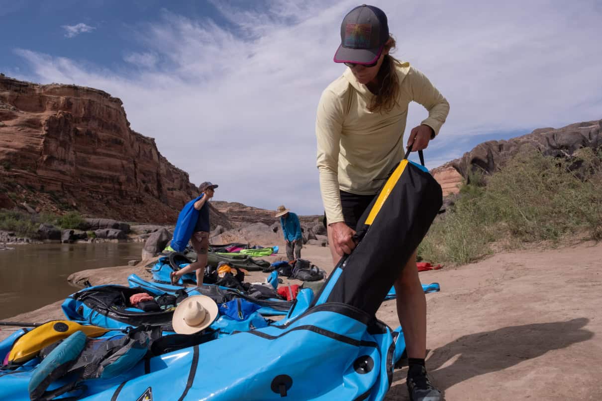 A woman pulling gear out from the internal storage of her packraft.