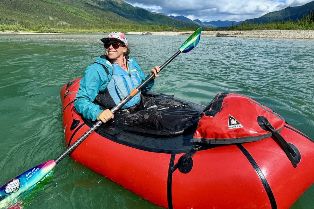 A woman paddling a packraft on a scenic and remote river.