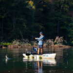 young man stands and fishes with a jerkbait from a kayak