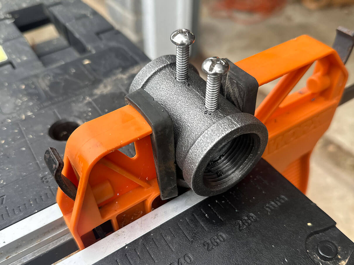 A pipe section held in orange clamps with two screws standing out from holes along the casting line