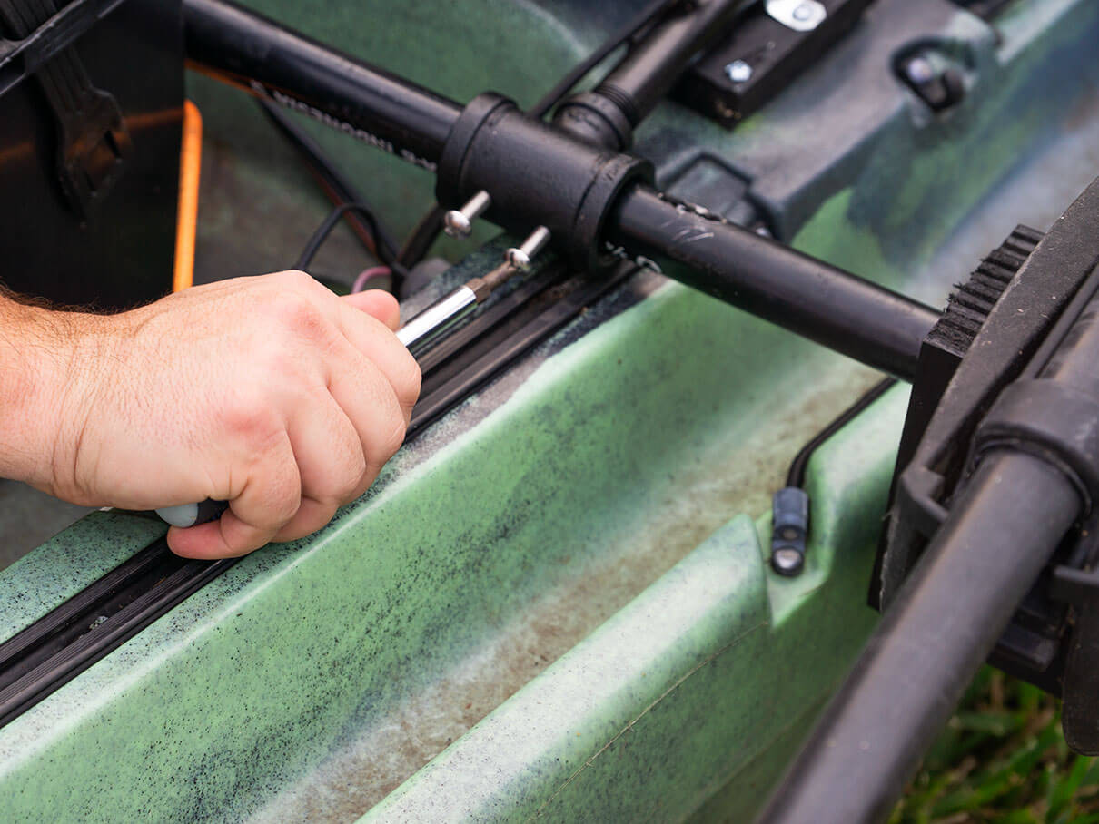 hand with screwdriver tightens a screw on the outrigger bar