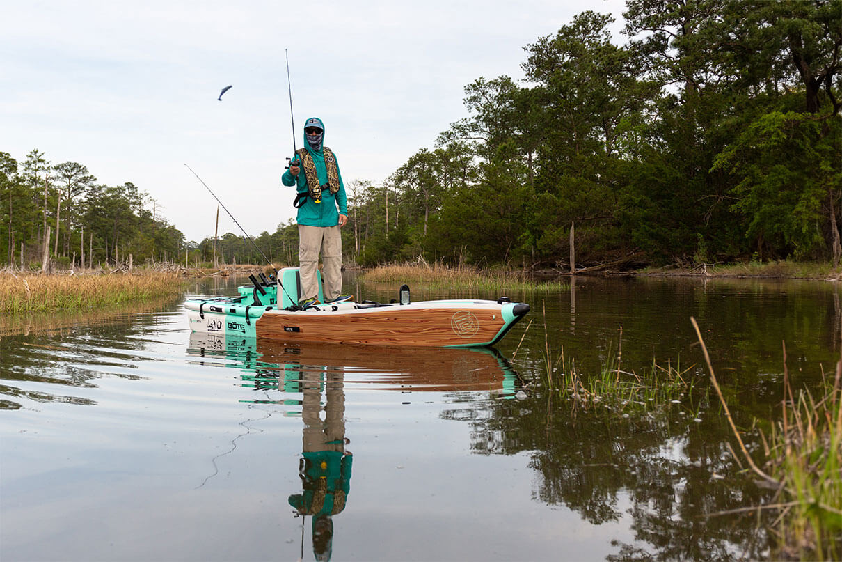 a person stands and pitches a lure from a BOTE inflatable kayak