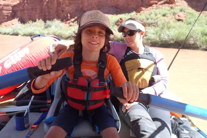 jen-booth1-jen-booth A teen rows a raft down a desert canyon with their parent beside them.